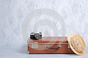 Travel carry on baggage, old fashioned suitcase, straw hat, film camera on grey background. Concept of travel with carry on luggag