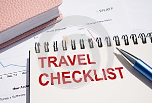 Travel Checklist text written on notepad with pen on financial documents