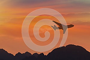travel concept background, airplane silhouette in sunset sky, international flight over mountains