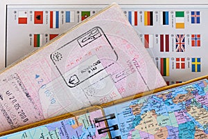 Travel concept background with map, passport with customs entry stamps and colorful national flags