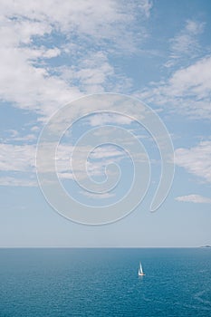 Travel concept background - small sailboat in the sea with blue sky with clouds.