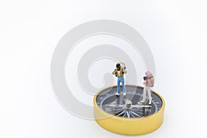 Travel Concept. Close up of two traveler miniature figure with backpack  standing on compass on white background and copy space