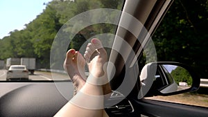Travel concept with convenience - female legs on car panel. Window and female legs with pedicure close-up against the