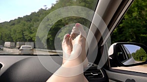 Travel concept with convenience - female legs on car panel. Window and female legs with pedicure close-up against the