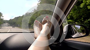 Travel concept with convenience - female legs on car panel. Window and female legs with pedicure close-up against the