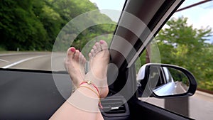 Travel concept with convenience - female legs on car panel. Windshield Window and female legs with pedicure and