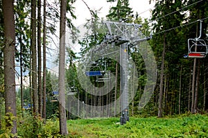 Travel concept. Couple of hikers or tourists enjoy the ride of chair lift ski lift and the beautiful mountain summer landscape