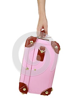 Travel concept. Female hand holding a pink suitcase isolated on white transparent background