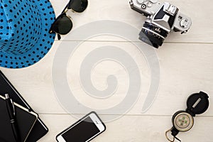 Travel concept flat lay overhead on white wood, with camera and sun glasses