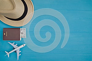 Travel Concept : Flat lay of straw hat, passport with money, plane model, on blue wooden background, with copy space.