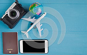 Travel Concept : Flat lay of vintage camera, smartphone, passport, golbe model and plane model, on blue wooden background, with c