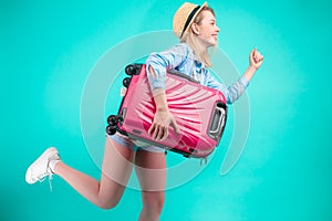 Travel concept. Full length studio portrait of beautiful tourist running with luggage.