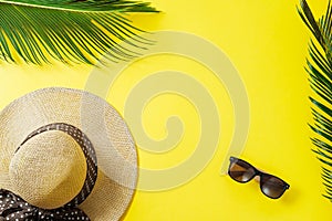 Travel concept: hat, palm leaf and sun glasses on yellow background. Top view, flat lay, space for text