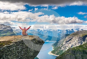 Travel concept. Hiker woman sitting on a cliff over a lake, Trolltunga, Norway. Artistic picture. Beauty world. The feeling of