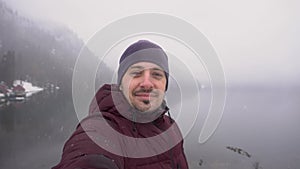 Travel concept. Man showing thumb up at Ritsa lake in Abkhazia in winter.