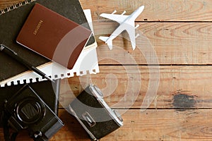 Travel concept with passport, camera, notebook and airplane on wooden background