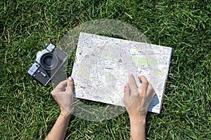 Travel concept photo with map of old european town and woman`s finger and old camera