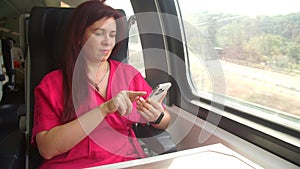 Travel concept by public transport. Woman using smartphone app taking pictures of the view while traveling in train