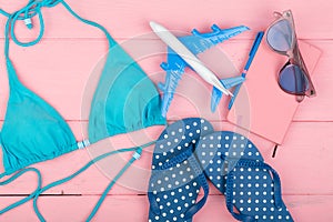 Travel concept - summer women& x27;s fashion with blue swimsuit, sunglasses, smart phone, headphones and little airplane