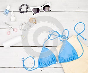 blue swimsuit, yellow shorts, cosmetics makeup, bijou and essentials on white wooden desk