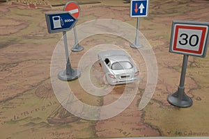 Travel concept. Toy car on vintage World map with road sign