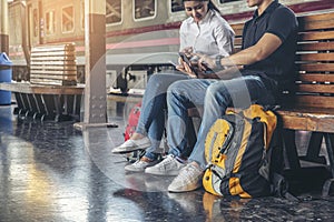 Travel concept.At train station, Young Tourists Couple of Love  pointing and planning happy holiday vacation.Asian Backpacker se