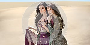 Travel concept. Two gordeous women sisters traveling in desert. Arabian Indian movie stars.