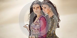 Travel concept. Two gordeous women sisters traveling in desert. Arabian Indian movie stars.