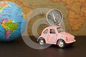 Travel concept and vacations. Pink retro car with world globe sphere. Planning summer vacations