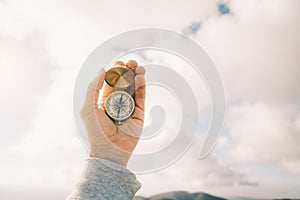 Travel concept. Vintage compass in male hands against the sky.