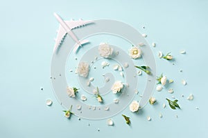 Travel concept with white plane and flowers, petals on blue background. Top view, flat lay. Copy space. Trip, vacation concept