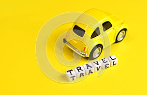 Travel concept with yellow toy car and cubes with `Travel` word.