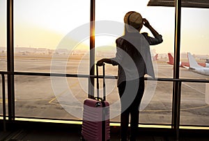 Travel concept with young woman holiding luggage in the airplane hall room at the sunlight in the airport terminal