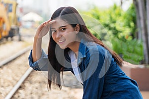 Travel concept. young woman looking for her friends covering eyes from the sun in the railway station. Traveller girl