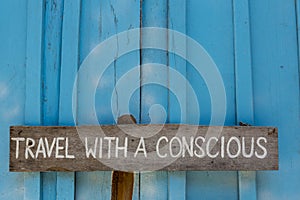 Travel with a conscious wooden sign on blue wooden background