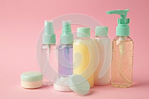 Travel cosmetic bottles on pink background. Minimalist bodycare beauty products for vacation or journey. Top view. Copyspace