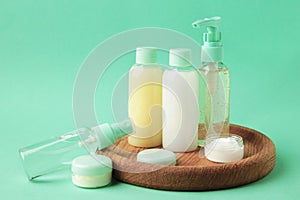 Travel cosmetic bottles with tray on mint background. Minimalist bodycare beauty products for vacation or journey. Top view.
