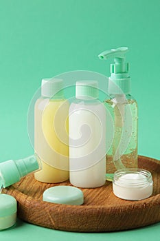 Travel cosmetic bottles with tray on mint background. Minimalist bodycare beauty products for vacation or journey. Top view.