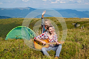 Travel couple enjoying wanderlast view, woman with arm up in excitement at mountain background. Happy family on vacation