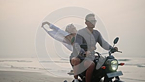 Travel couple ride motorcycle along sea beach on sunrise. Intraframe installation from bike to people. Tourists drive