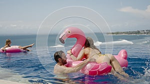 Travel couple swim in infinity pool on luxury villa, woman tries to jump
