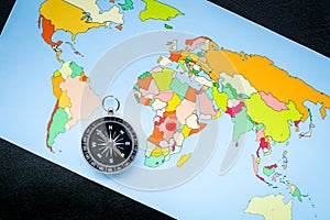 Travel direction and trip planning concept with compass and map of the world on black background top view