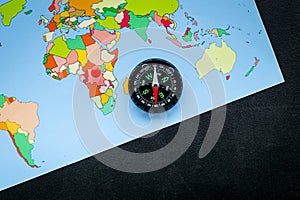 Travel direction and trip planning concept with compass and map of the world on black background top view