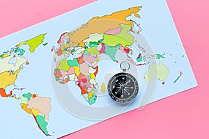 Travel direction and trip planning concept with compass and map of the world on pink background top view