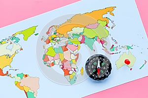 Travel direction and trip planning concept with compass and map of the world on pink background top view