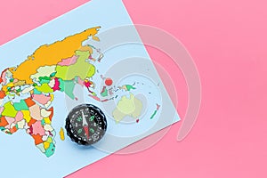 Travel direction and trip planning concept with compass and map of the world on pink background top view space for text