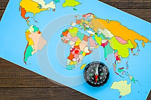 Travel direction and trip planning concept with compass and map of the world on wooden background top view