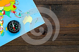 Travel direction and trip planning concept with compass and map of the world on wooden background top view mock up