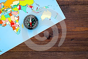 Travel direction and trip planning concept with compass and map of the world on wooden background top view mock up