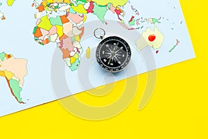 Travel direction and trip planning concept with compass and map of the world on yellow background top view space for